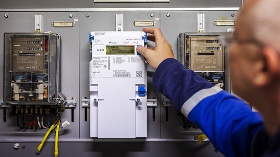 Ein Zaehlermonteur im Auftrag der EWZ installiert einen neuen Smart Meter-Stromzaehler neben alten Stromzaehlern in einem Mehrfamilienhaus