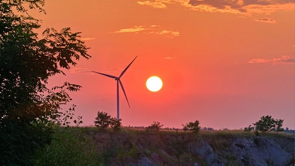  Ein Windrad steht neben der untergehenden Sonne am Großtagebau Vereinigtes Schleenhain der Mitteldeutsche Braunkohlengesellschaft mbH