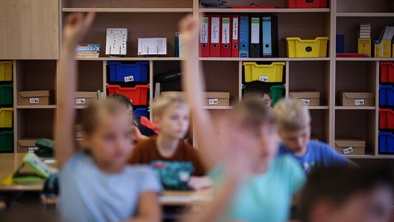 Drittklässler melden sich während der Schulstunde.