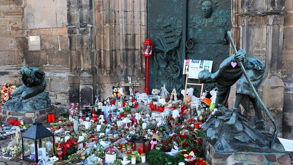 Blumen,Kerzen und Gedenksteine liegen vor dem Portal der Johanniskirche.