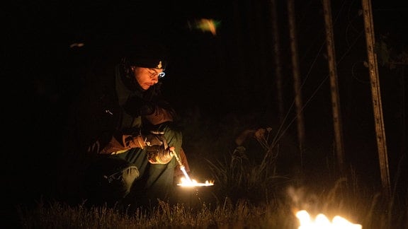 Winzer entzünden zahlreiche kleine kontrollierte Feuer in einem Weinberg an den Rebstöcken.
