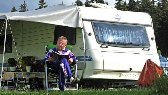 Auf dem Campingplatz "Paulfeld" in Catterfeld bei Friedrichroda genießt ein Rentner den sonnigen Nachmittag vor seinem Wohnwagen.