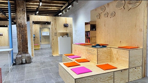 Blick in die Ausstellung: Auf einem simplen Holzaufbau liegen einfarbige Bücher.