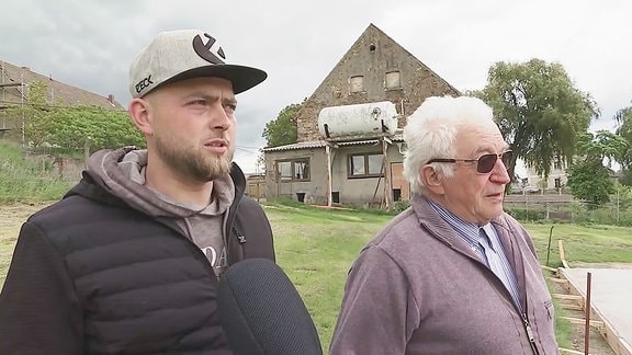 Zwei Männer stehen auf einer Wiese.