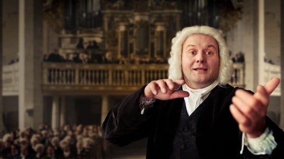Ein Mann mit weißer gelockert Perücke streckt seine Arme aus.